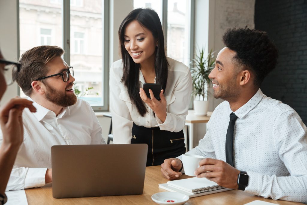 cherful positive young colleagues using laptop computer.